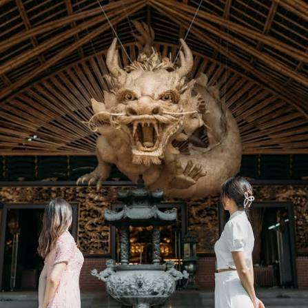 Visitors viewing an ornate dragon sculpture inside the temple hall