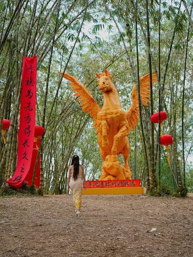 A large phoenix sculpture decorated with red lanterns and banners